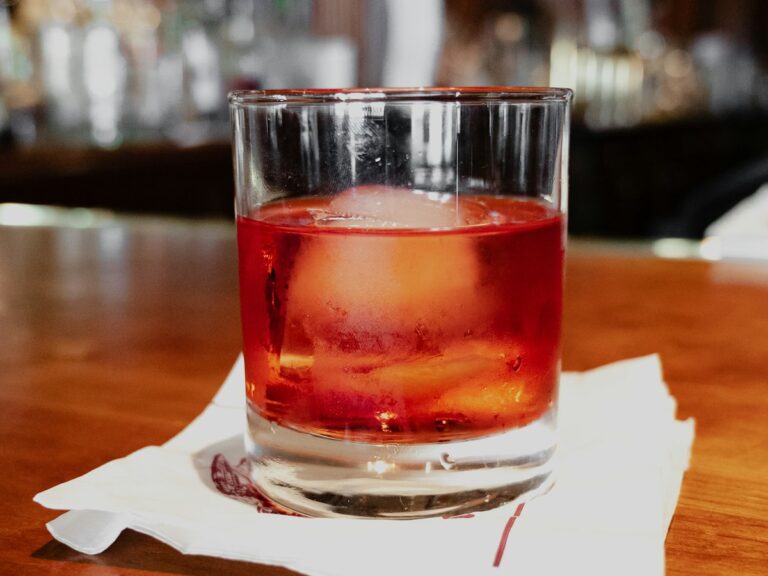 Illustrative photo of a Negroni over a large ice cube at a bar